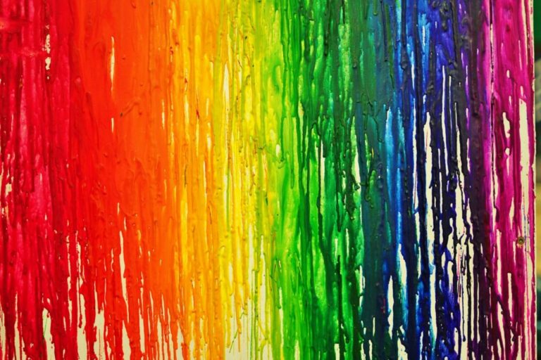 LGBTQ pride rainbow flag painted with colorful bleeding paint streaks on a wall