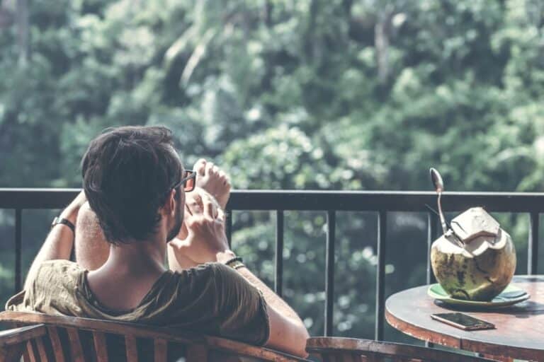 man relaxing on porch with sunglasses admiring the view of trees