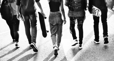 black and white photo of teenagers walking in street