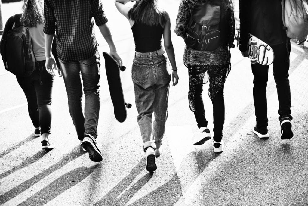 black and white photo of teenagers walking in street