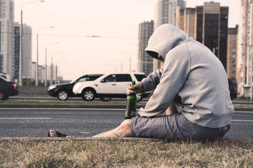 man drinking beer on curb
