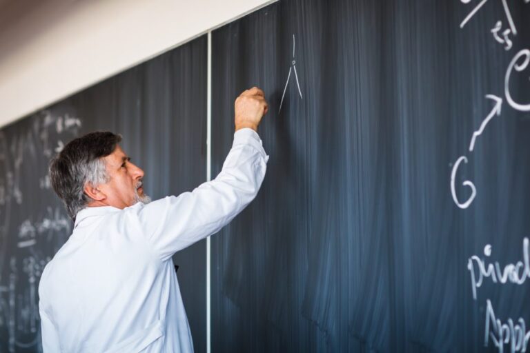 Doctor writing chemical compound formulas on chalkboard