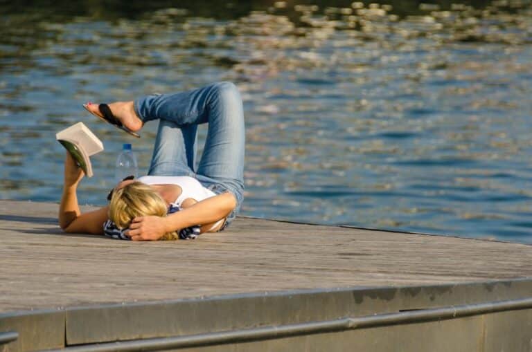 Woman laying on boat dock and reading book